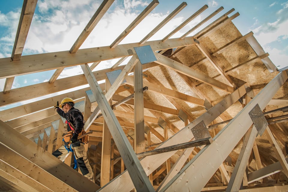 Nachhaltig bauen mit Holz - Bauarbeiter beim Bau des Dachstuhls eines Holzhauses 
