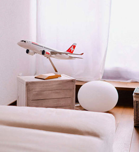 Modell eines SwissAir Flugzeugs auf einer Holzkiste als Deko in einer hellen Wohnung
