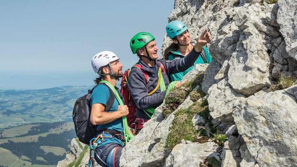 Drei Bergsteiger schauen zum Berggipfel und besprechen den sicheren Aufstieg
