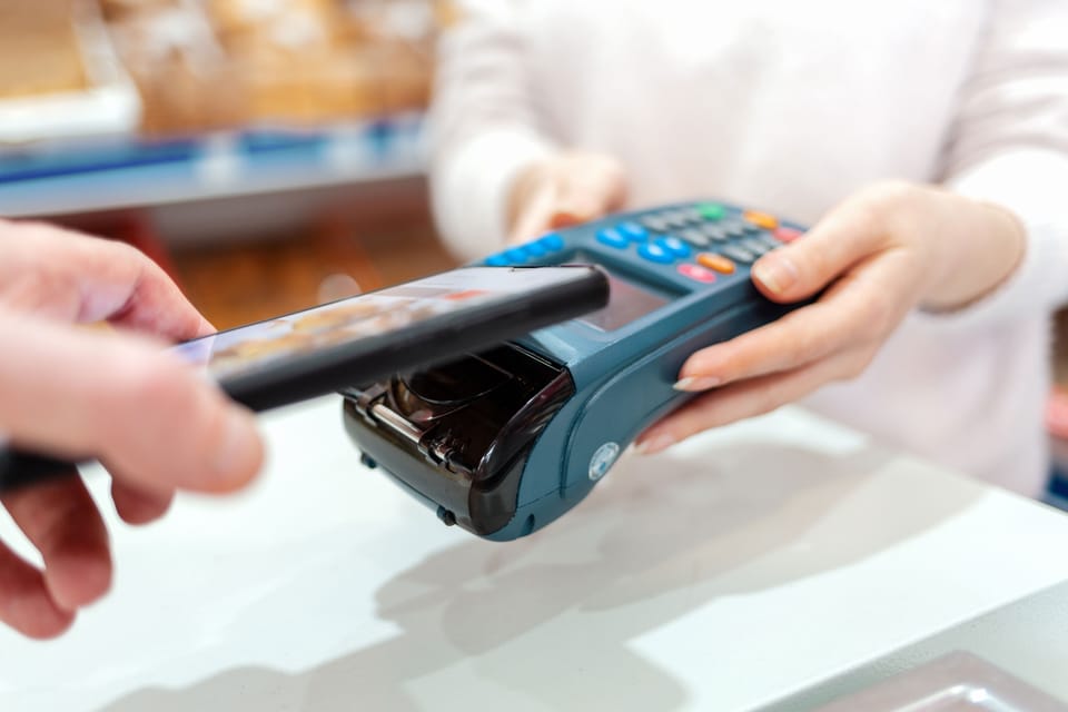 Ein Kunde bezahlt in einem Geschäft mit dem Smartphone an einem Zahlterminal